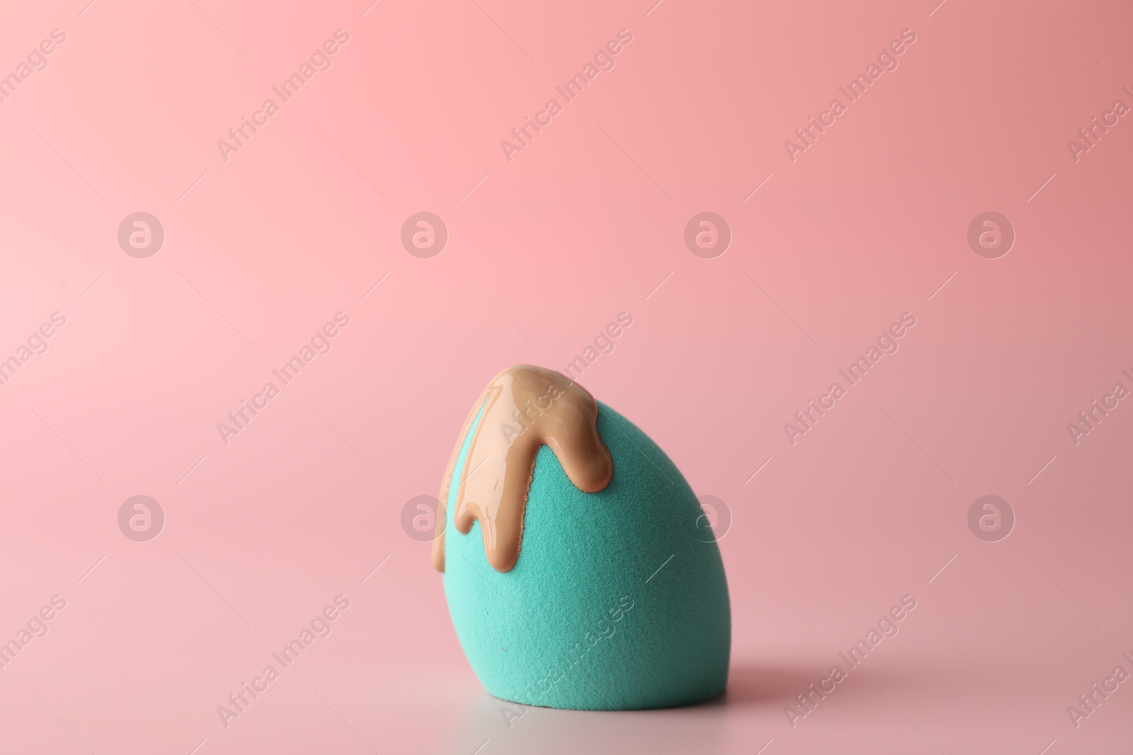 Photo of Makeup sponge with skin foundation on pink background