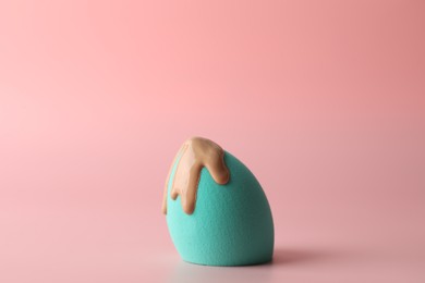 Photo of Makeup sponge with skin foundation on pink background