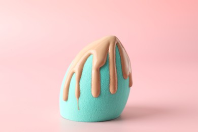 Photo of Makeup sponge with skin foundation on pink background