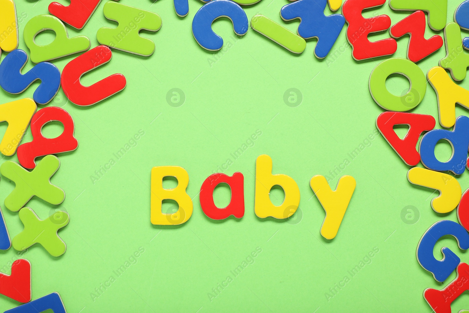 Photo of Word Baby made of magnetic letters on green background, flat lay. Learning alphabet