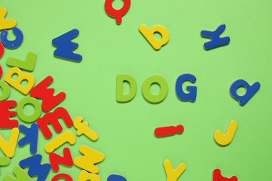 Photo of Word Dog made of magnetic letters on green background, flat lay. Learning alphabet