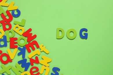 Photo of Word Dog made of magnetic letters on green background, flat lay. Learning alphabet