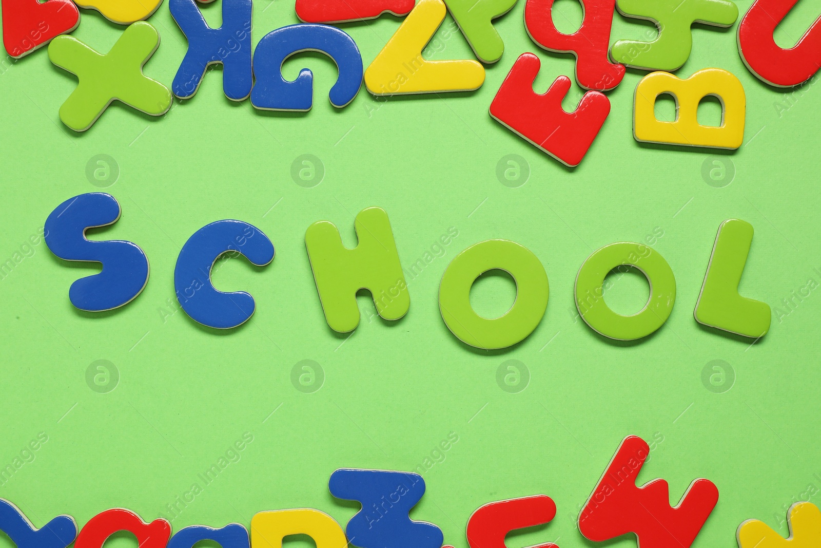 Photo of Word School made of magnetic letters on green background, flat lay. Learning alphabet