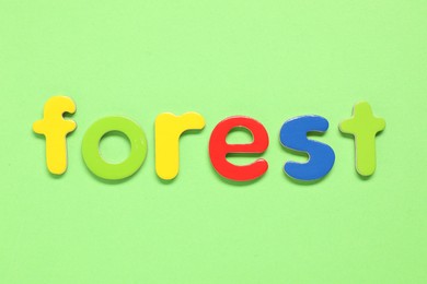 Word Forest made of magnetic letters on green background, top view. Learning alphabet