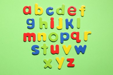 Photo of Alphabetical order. Bright magnetic letters on green background, top view