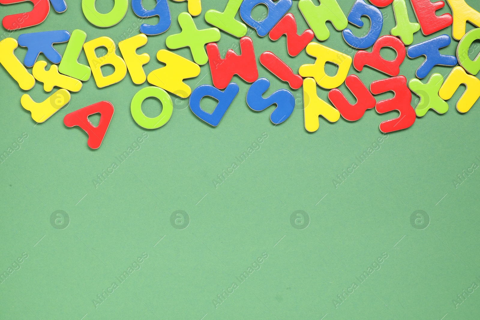 Photo of Learning alphabet. Magnetic letters on green background, flat lay. Space for text