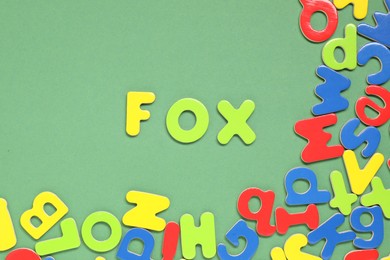 Word Fox made of magnetic letters on green background, flat lay. Learning alphabet