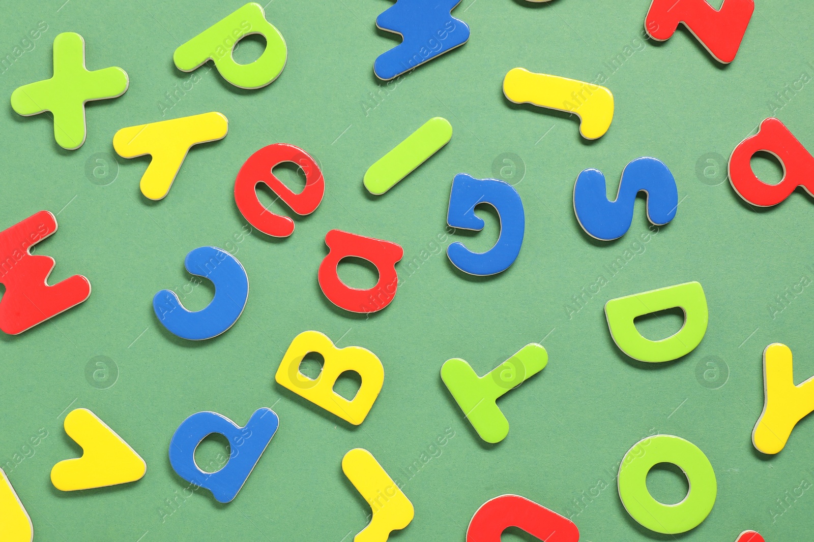 Photo of Learning alphabet. Magnetic letters on green background, flat lay