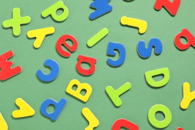 Learning alphabet. Magnetic letters on green background, flat lay