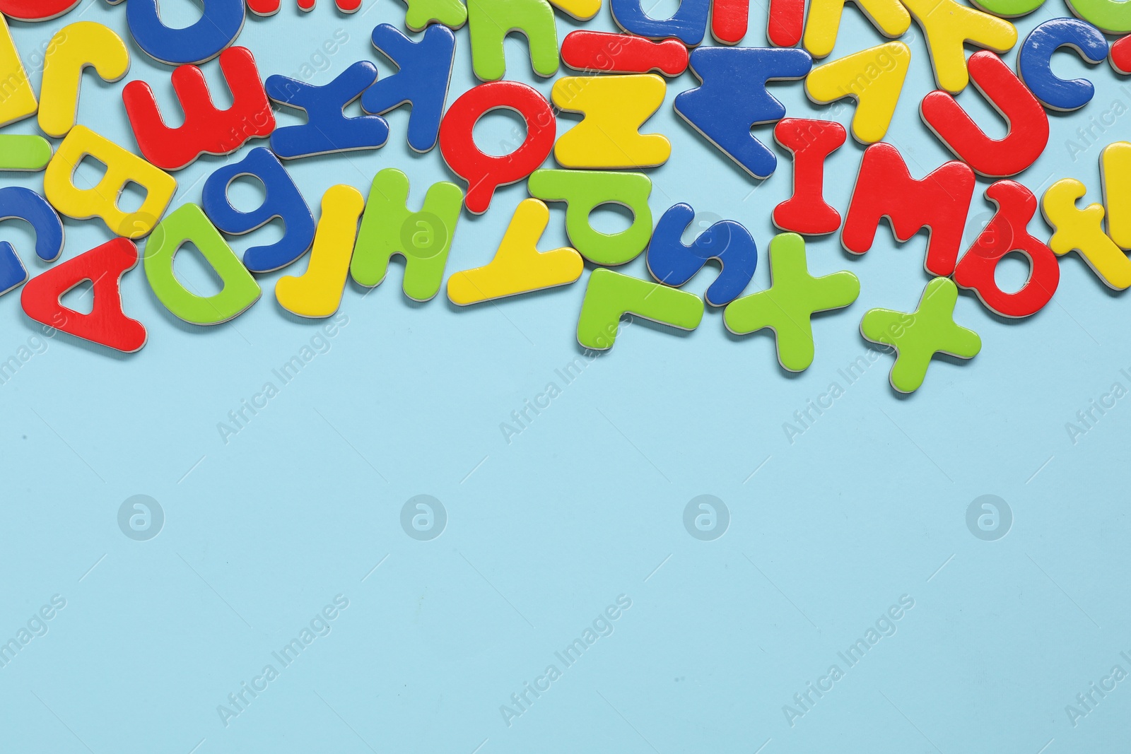 Photo of Learning alphabet. Magnetic letters on light blue background, flat lay. Space for text