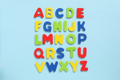 Alphabetical order. Bright magnetic letters on light blue background, top view