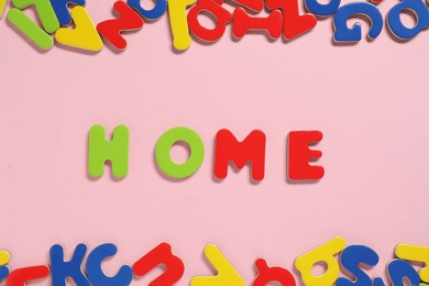 Word Home made of magnetic letters on pink background, flat lay. Learning alphabet