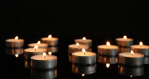 Many burning tealight candles on mirror surface against black background. Banner design