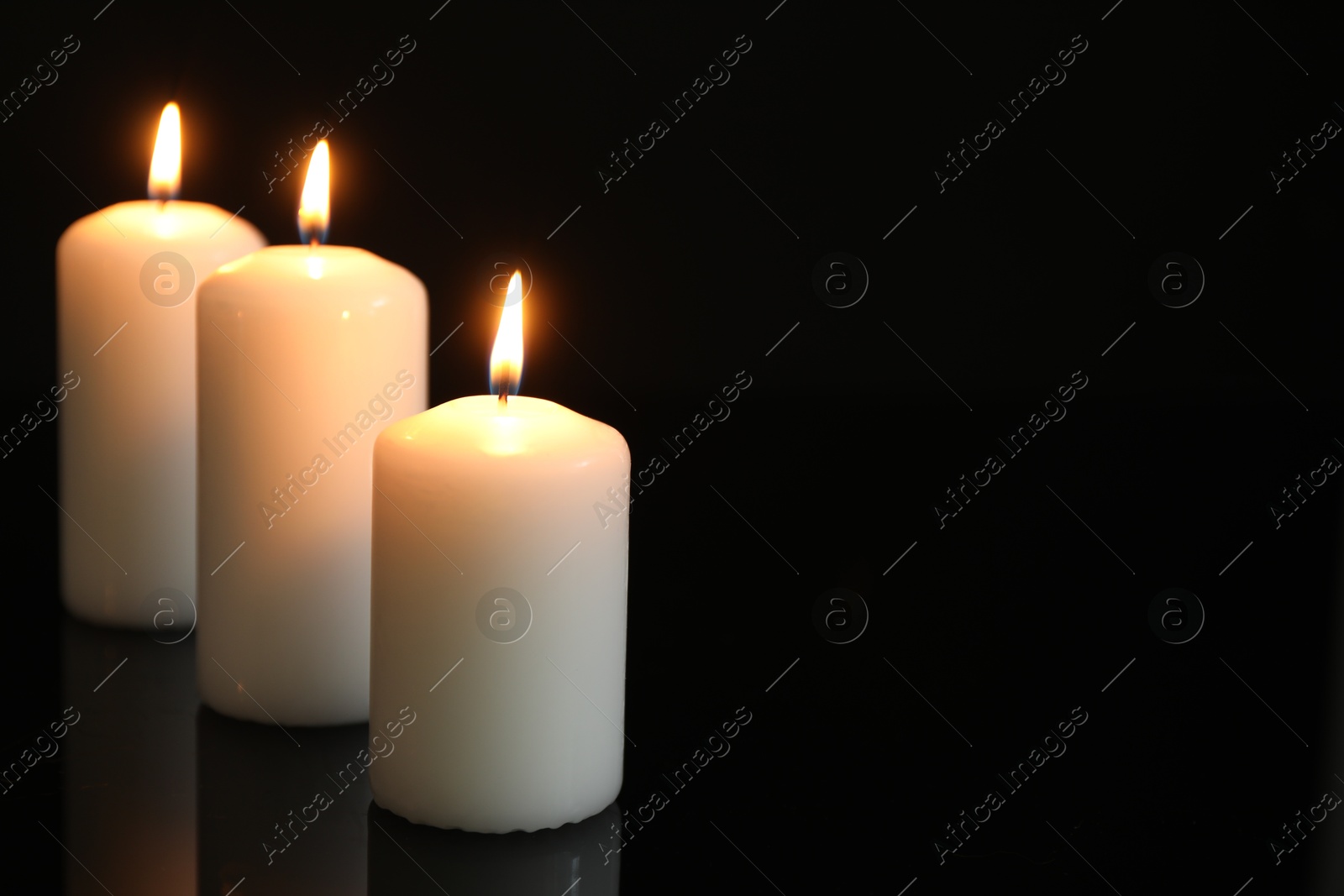 Photo of Many burning candles on mirror surface against black background. Space for text