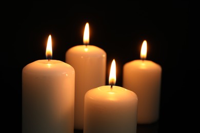 Photo of Many burning candles on black background, closeup