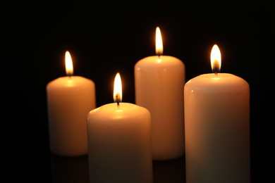 Photo of Many burning candles on black background, closeup