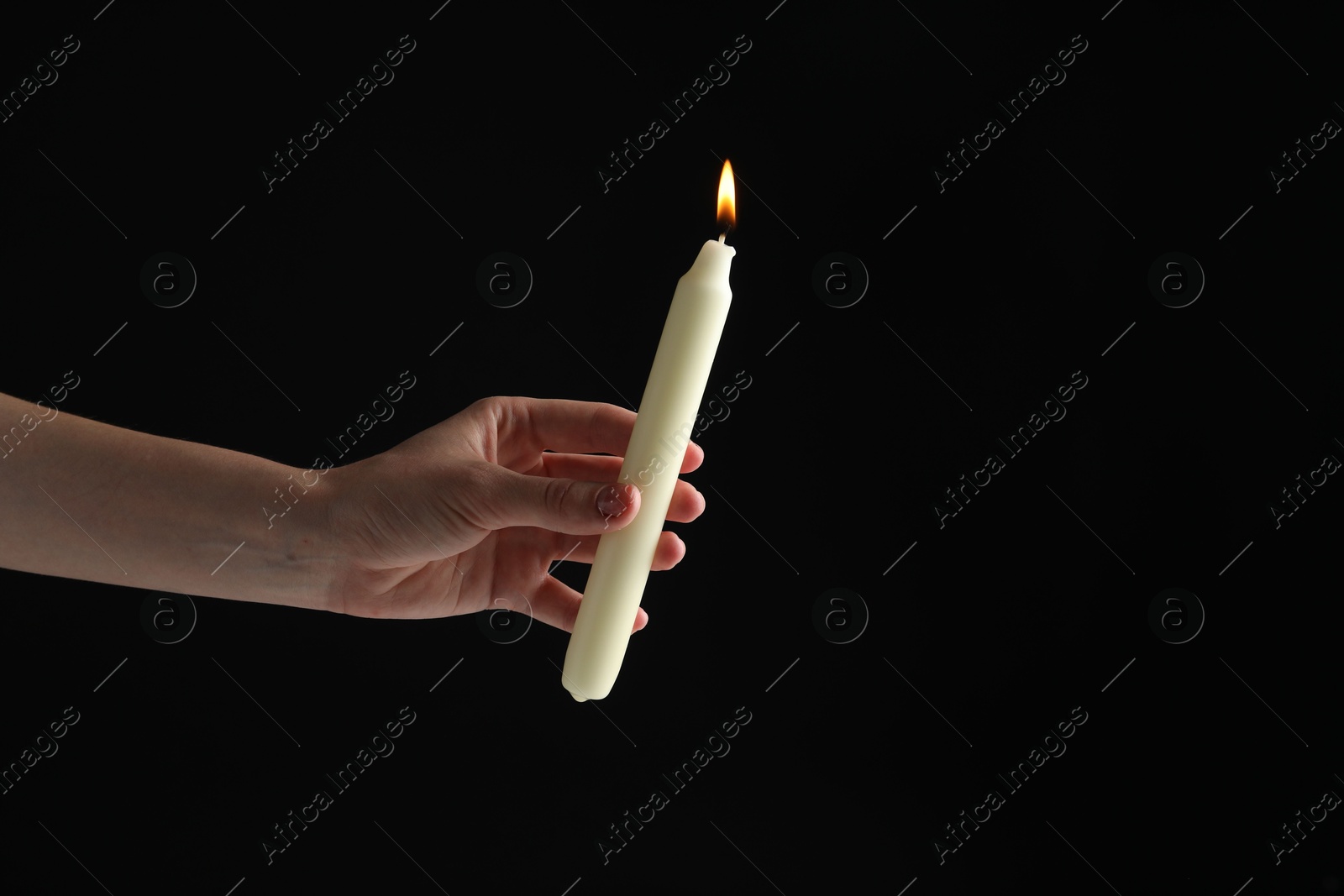 Photo of Woman holding burning candle on black background, closeup