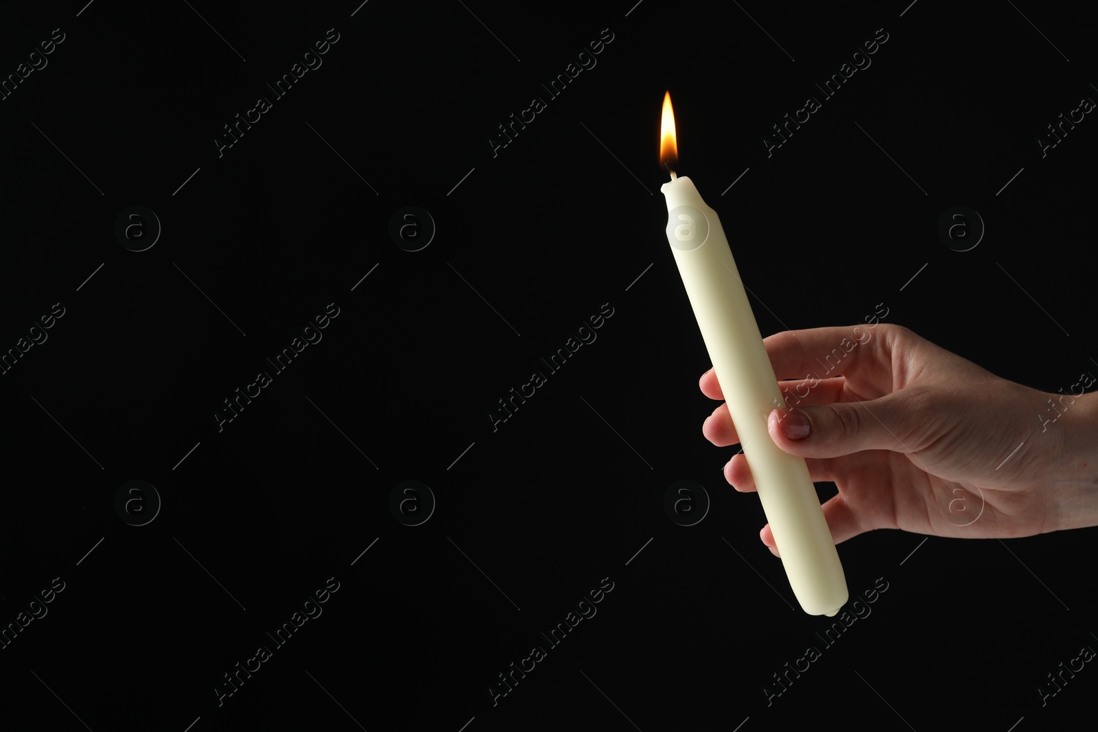 Photo of Woman holding burning candle on black background, closeup. Space for text