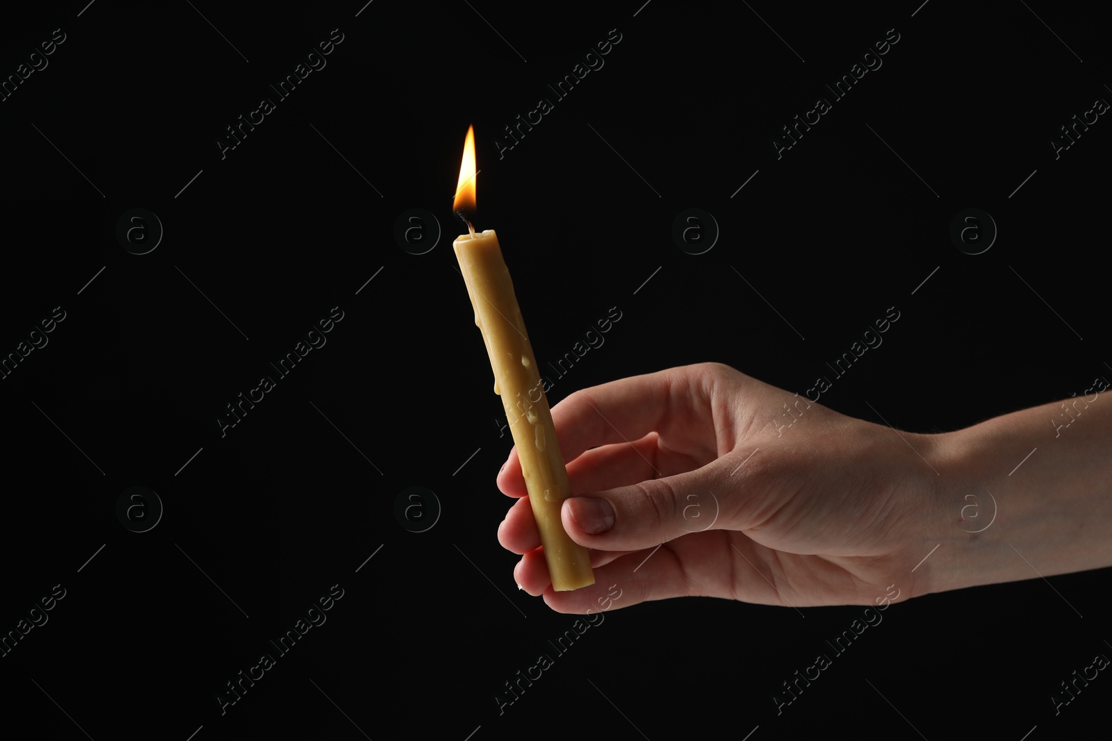 Photo of Woman holding burning church candle on black background, closeup