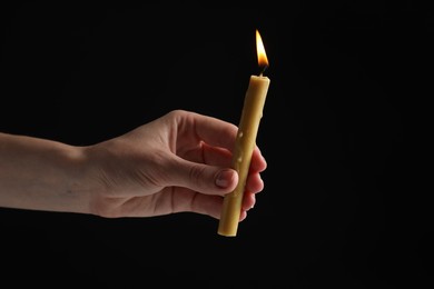 Photo of Woman holding burning church candle on black background, closeup