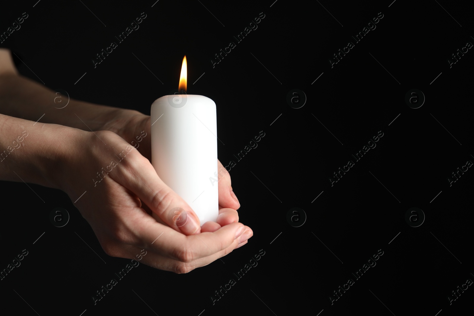 Photo of Woman holding burning candle on black background, closeup. Space for text