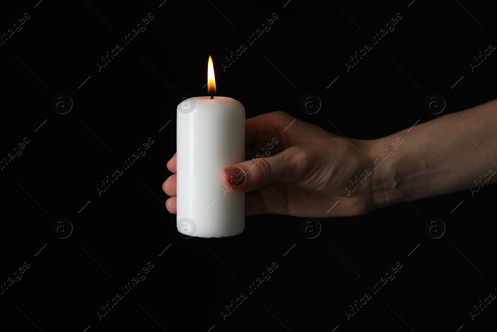 Photo of Woman holding burning candle on black background, closeup