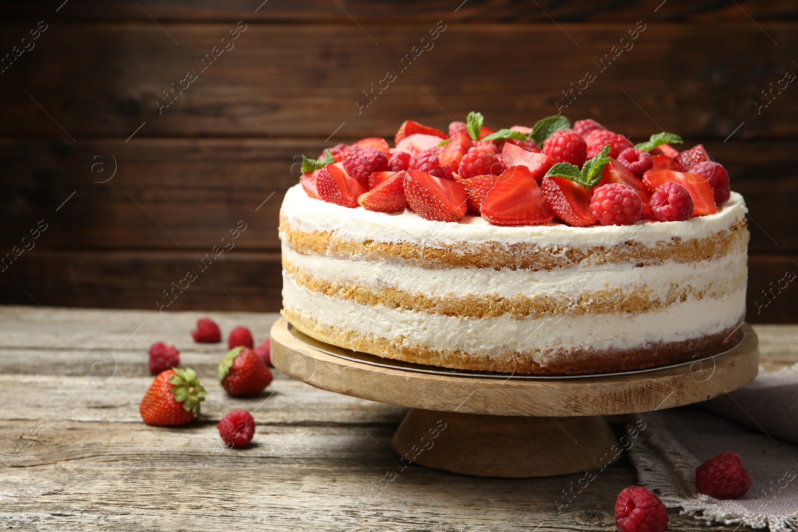 Photo of Tasty sponge cake with fresh berries and mint on wooden table