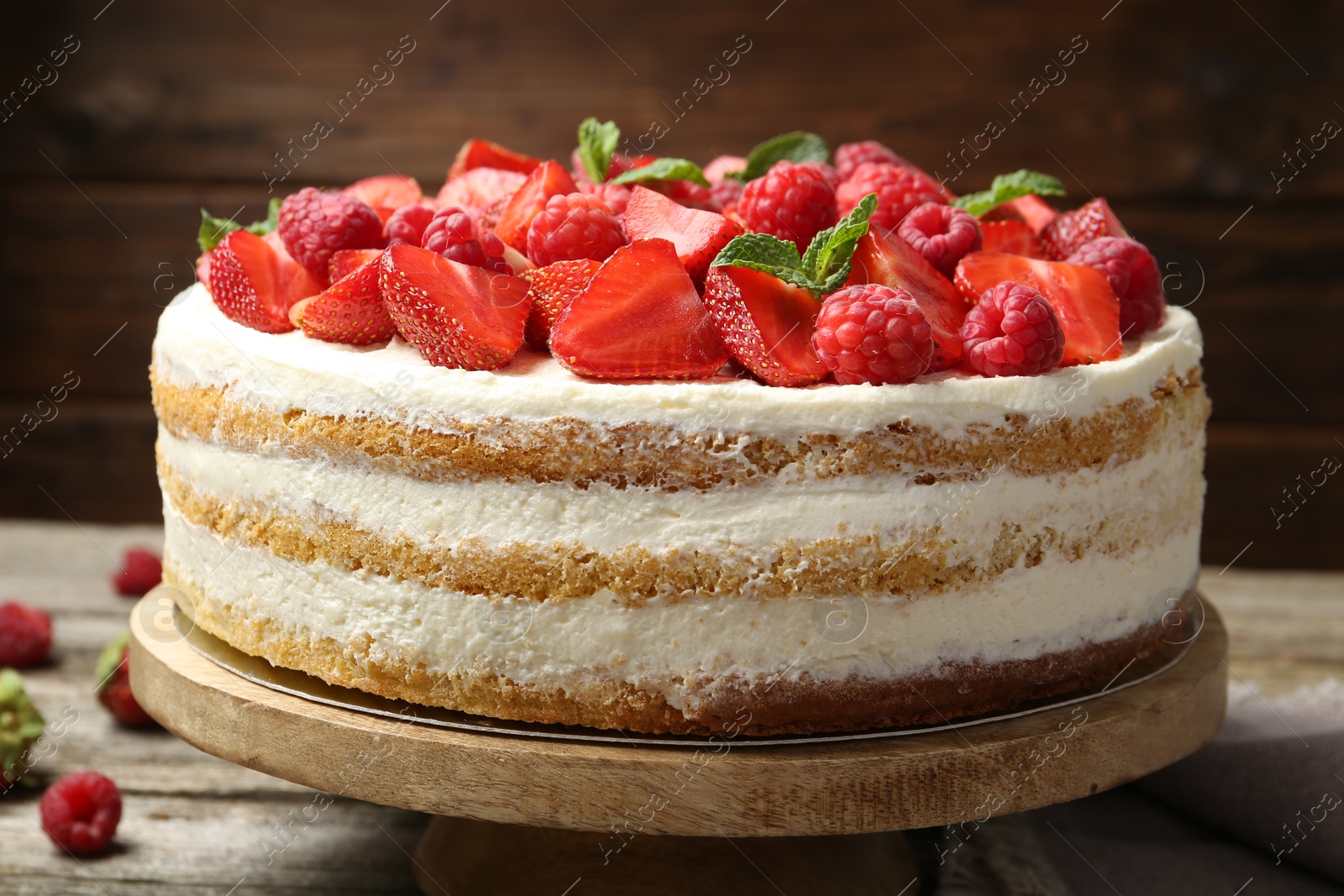 Photo of Tasty sponge cake with fresh berries and mint on wooden table, closeup