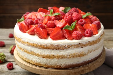 Tasty sponge cake with fresh berries and mint on wooden table, closeup