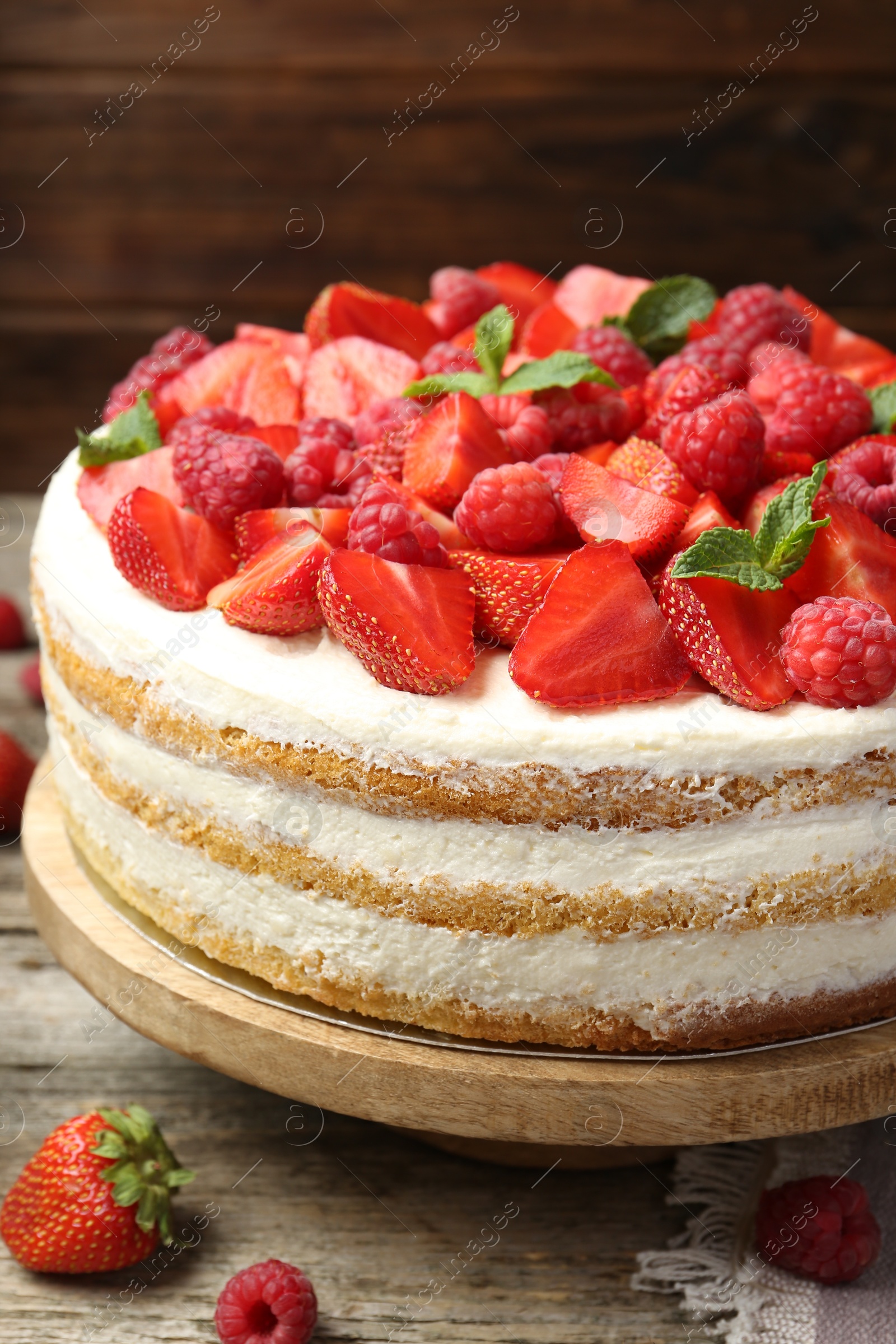 Photo of Tasty sponge cake with fresh berries and mint on wooden table, closeup