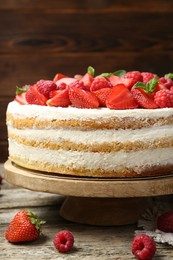 Tasty sponge cake with fresh berries and mint on wooden table