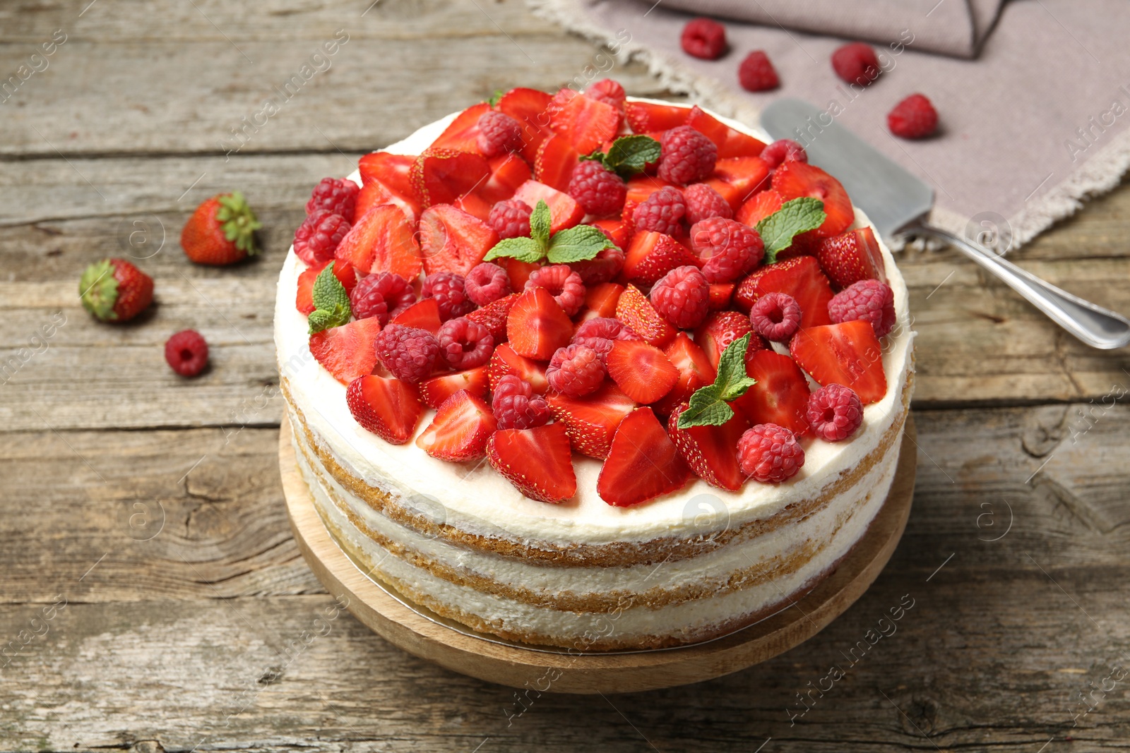 Photo of Tasty sponge cake with fresh berries and mint on wooden table