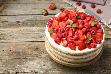 Photo of Tasty sponge cake with fresh berries and mint on wooden table, space for text