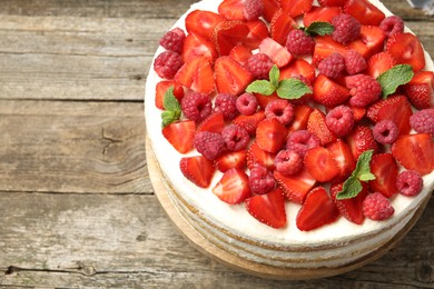 Photo of Tasty sponge cake with fresh berries and mint on wooden table, above view. Space for text