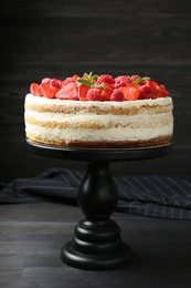 Photo of Tasty sponge cake with fresh berries and mint on dark gray wooden table