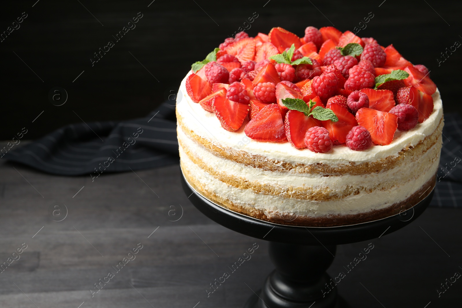 Photo of Tasty sponge cake with fresh berries and mint on dark gray wooden table, space for text