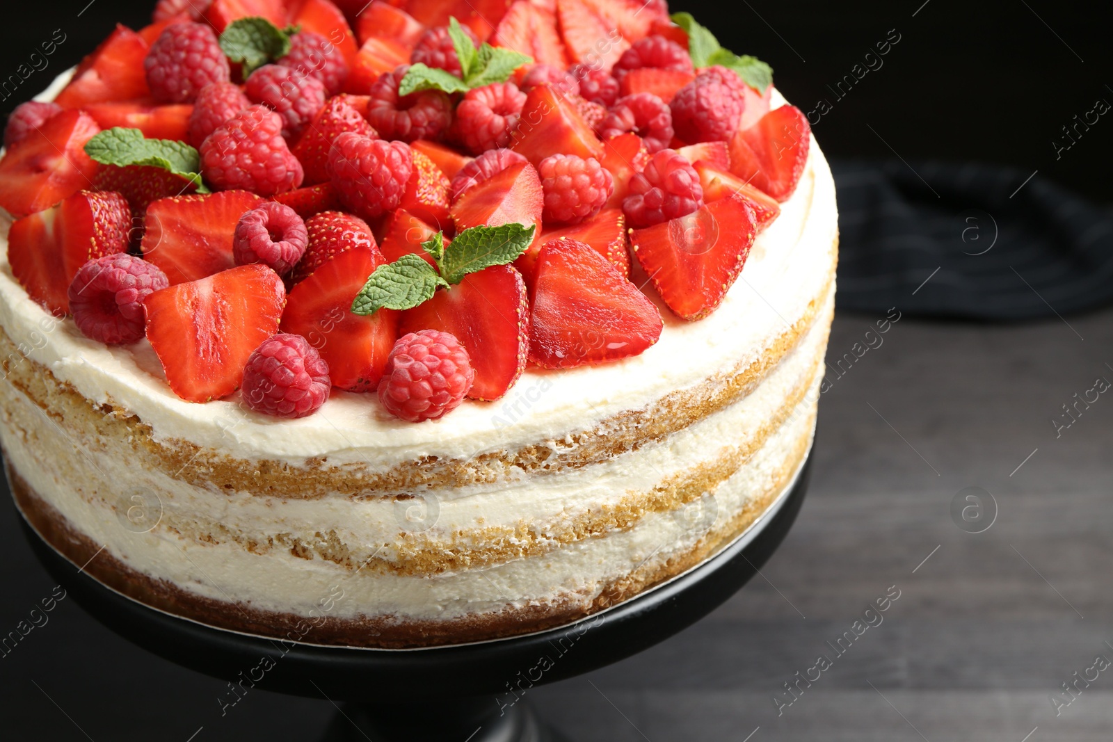 Photo of Tasty sponge cake with fresh berries and mint on dark gray table, closeup