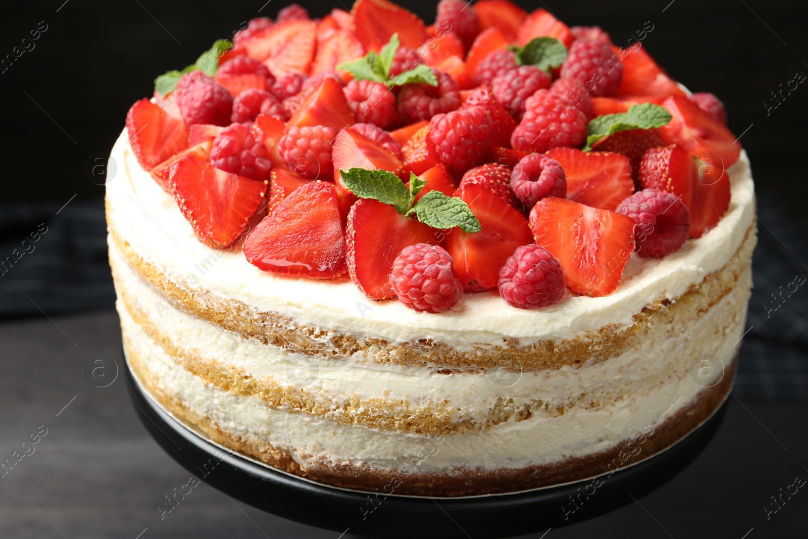 Photo of Tasty sponge cake with fresh berries and mint on dark gray table, closeup