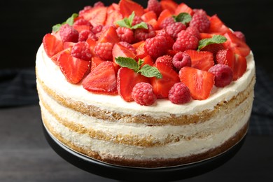 Photo of Tasty sponge cake with fresh berries and mint on dark gray table, closeup