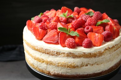 Photo of Tasty sponge cake with fresh berries and mint on dark gray table, closeup