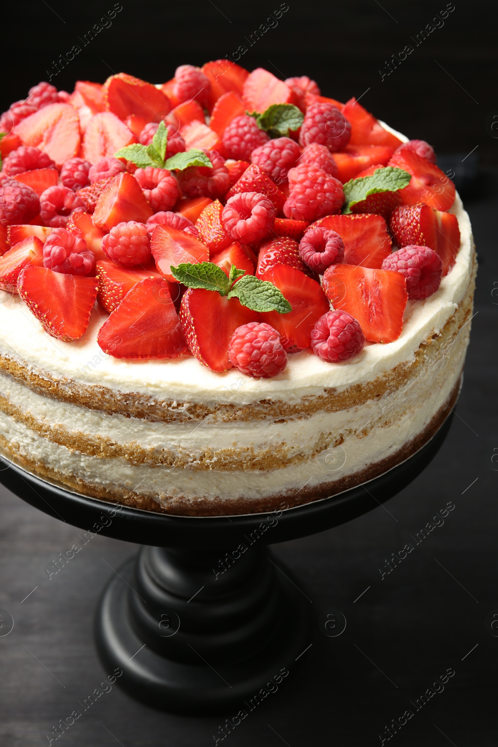 Photo of Tasty sponge cake with fresh berries and mint on dark gray table, closeup