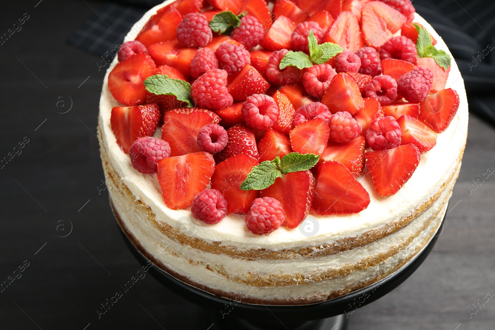 Photo of Tasty sponge cake with fresh berries and mint on dark gray table, closeup