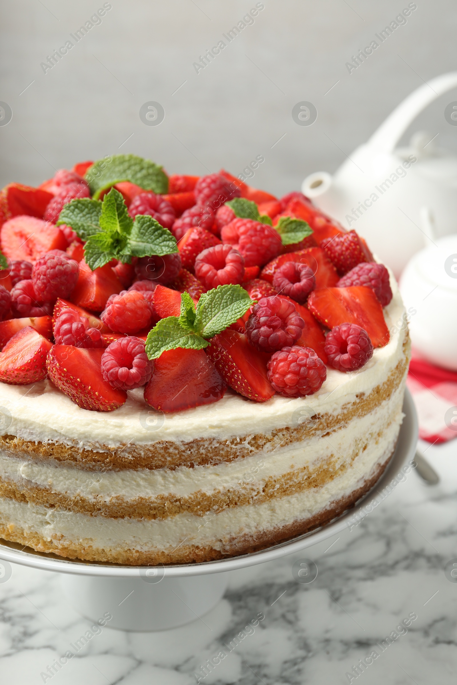 Photo of Tasty sponge cake with fresh berries and mint on white marble table, closeup