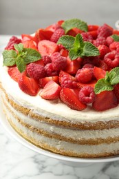 Photo of Tasty sponge cake with fresh berries and mint on white marble table, closeup