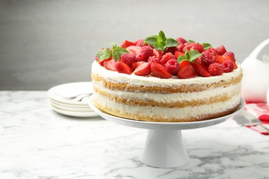 Tasty sponge cake with fresh berries and mint on white marble table