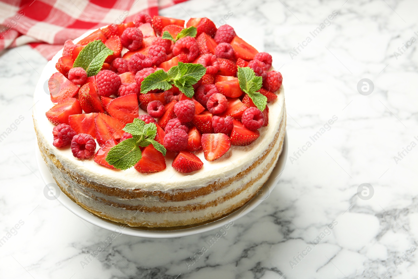 Photo of Tasty sponge cake with fresh berries and mint on white marble table, closeup