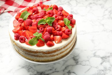 Photo of Tasty sponge cake with fresh berries and mint on white marble table, closeup