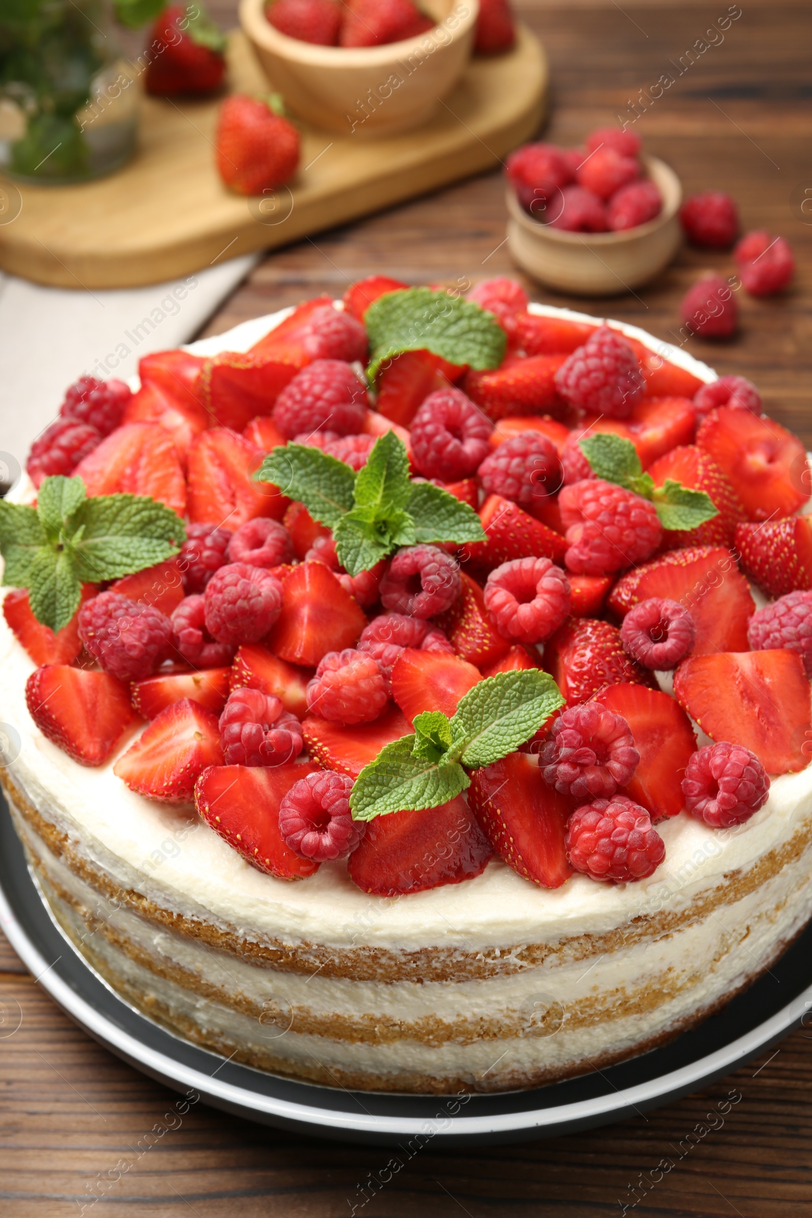 Photo of Tasty sponge cake with fresh berries and mint on wooden table, closeup