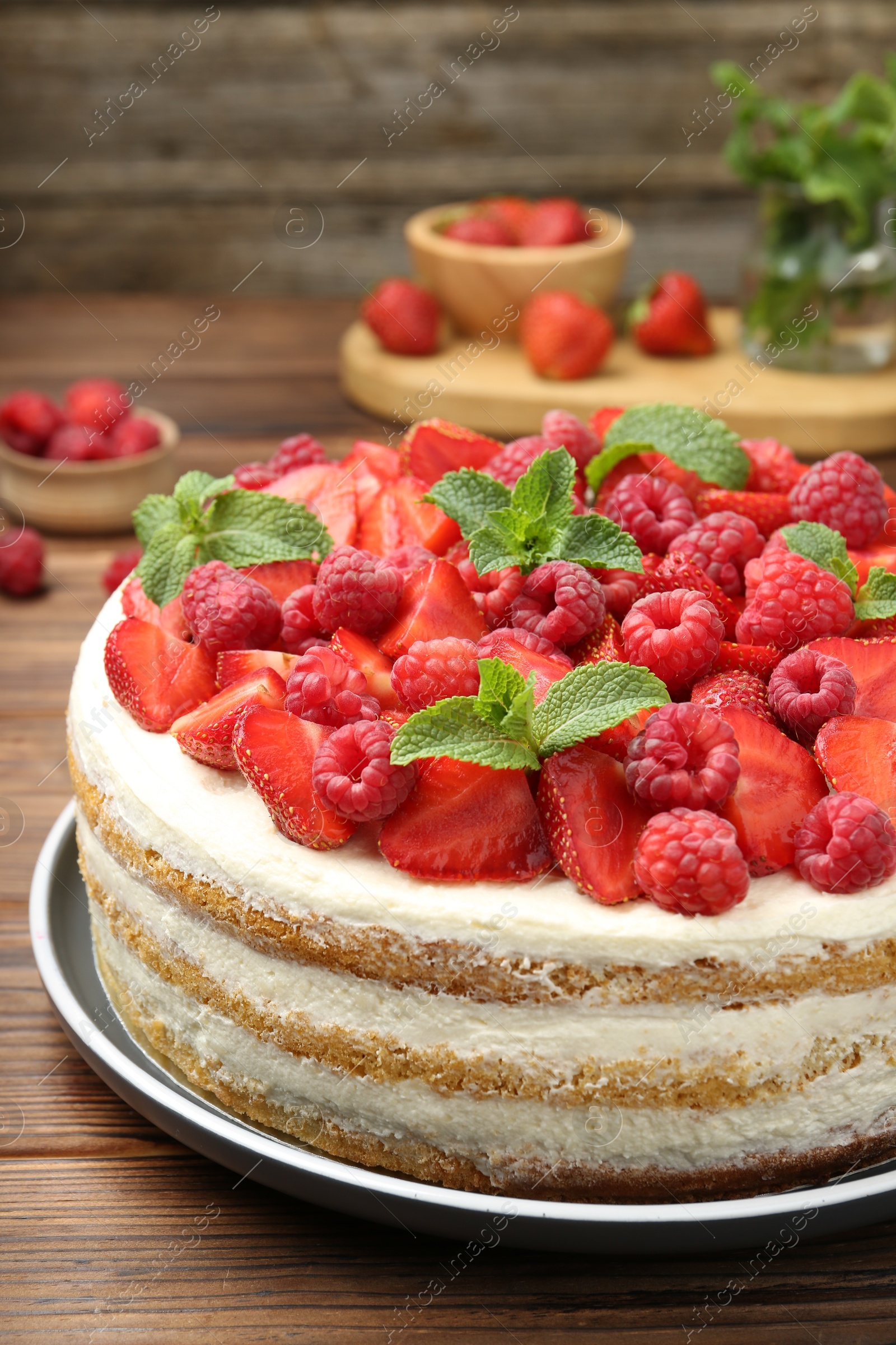 Photo of Tasty sponge cake with fresh berries and mint on wooden table, closeup