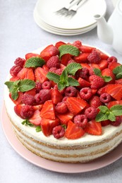 Photo of Tasty sponge cake with fresh berries and mint on light gray table, closeup